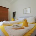 Ein Schlafzimmer mit Bett, Schrank und Nachttisch. Auf dem Bett liegen Handtücher und Kissen.