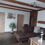 Living room with brown sofa, wooden beams, and plant.