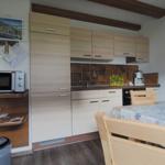 Kitchen with wooden furniture, microwave, coffee machine, and dining table with tablecloth.