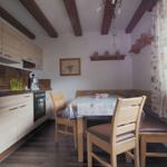 Kitchen with dining table, wooden chairs, and beams on the ceiling.