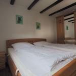 Bedroom with wooden bed, wardrobe, and nightstand.