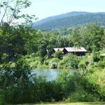 House by the lake with forest and mountain in the background.