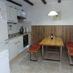 Kitchen with dining area, wooden table, benches with red cushions, and kitchen counter.