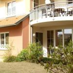 Haus mit Balkon, Terrasse und Garten. Fenster und Türen sind sichtbar.