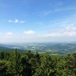 Wide view over forested hills and valleys under blue sky with white clouds.