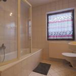 Bathroom with bathtub, shower, sink, and toilet. Window with curtain.