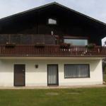 A two-story house with a balcony and windows. Lawn in front of the house.