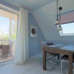 Esszimmer mit Tisch, Stühlen und Blick auf Balkon. Wandfarbe blau-weiß.
