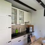 Kitchen with white cabinets, sink, stove, and dining table with chairs.