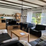 Living room with sofa, table, and TV. Window with curtains. Wooden floor.