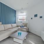 Wohnzimmer mit Sofa, Couchtisch und TV. Wand mit Streifen, Fenster mit Blick.