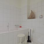 Bad mit Badewanne, Toilette und kleinem Regal mit Segelboot.