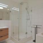 Badezimmer mit Dusche, Badewanne und Waschbecken mit Holzschrank.