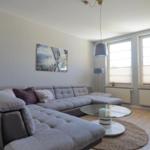 Ein Wohnzimmer mit grauem Sofa, Glas-Tisch und Fenstern mit Jalousien.