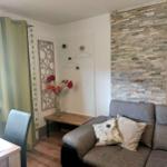 Living room with sofa, table, chairs, and stone wall. Window with green curtains.