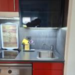 Kitchen with sink, stove, and dishwasher. Red-black fronts and illuminated worktop.