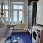 Badezimmer mit Dusche, Waschmaschine und Fenster.