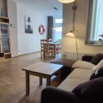 Wohn- und Essbereich mit Sofa, Tisch und Fernseher. Wandbild und Rettungsring sichtbar.