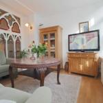 Wohnzimmer mit Holzmöbeln, TV, Couch und dekorativen Wandverkleidungen.