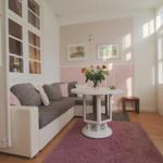 Wohnzimmer mit Sofa, runden Tisch und Blumen. Wand in Rosa-Beige-Ton.