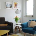 Ein Wohnzimmer mit Sofa, blauem Sessel, Tisch und Blumen.