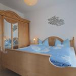 Schlafzimmer mit Holzbett, Kleiderschrank und Wanddekoration.