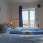 Schlafzimmer mit Bett, Vorhang und Balkontür. Wanddekoration mit Fischmotiv.