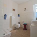 Bad mit Dusche, Toilette und Waschbecken. Fenster, Handtuchhalter und dekorative Elemente.