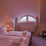 Schlafzimmer mit Doppelbett, Bogenfenster und Holzschrank. Bodenfliesen und Wandbild sichtbar.
