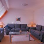 Wohnzimmer mit grauen Sofas, Glas-Tisch und Fenster mit Vorhängen.