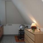 Küche mit Esstisch, Schrank und Lampe unter Dachschrägen.