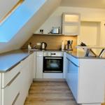 Küche mit Dunstabzug, Herd und Kühlschrank unter Dachschrägen.