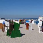 Strand mit vielen Liegestühlen und Blick auf das Meer unter blauem Himmel.