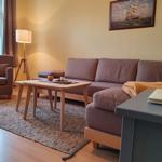 Wohnzimmer mit Sofa, Sessel, Tisch und Bild an der Wand.