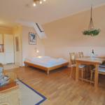 Ein Schlafzimmer mit Dachfenster, Esstisch, Küchenbereich und Wohnbereich mit Sitzgelegenheiten.