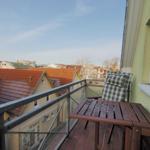 Terrasse mit Tisch und Stuhl, Blick auf Dächer und Straße.