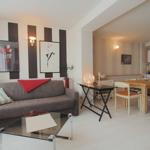 Wohn- und Essbereich mit Sofa, Esstisch und Küche im Hintergrund.