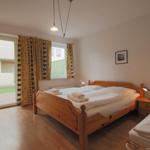 Schlafzimmer mit Doppelbett, kleinem Bett und Blick auf den Hof.