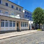 Fassade eines Ferienhauses mit Balkon und großen Fenstern an einer gepflasterten Straße.