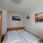 Schlafzimmer mit Doppelbett, Wandbildern und Holzelementen an der Wand.