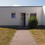Haus mit weißen Wänden, Eingangstür und gepflastertem Weg.