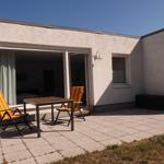 Terrasse mit Tisch und zwei Stühlen vor einem Haus mit Schiebetür.