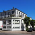 Wohnhaus mit Balkonen und Fenstern an sonnigem Tag.