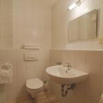 Badezimmer mit Waschbecken, Toilette, Spiegel und Handtuchhalter.