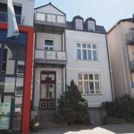 Haus mit Eingangstür, Balkonen und Fenstern. Nummer 9. Vor dem Haus steht ein Baum.