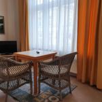 Zimmer mit Esstisch, zwei Stühlen, Fernseher und Fenster mit Vorhängen.