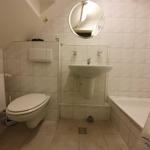 Badezimmer mit Toilette, Waschbecken und Badewanne unter Dachschrägen.
