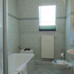 Badezimmer mit Badewanne, Dusche, Toilette und Waschbecken. Fenster mit Jalousie.