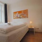 Schlafzimmer mit Bett, Nachttisch, Kleiderschrank und Wandbild