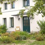 Haus mit grüner Tür und Vorgarten unter Apfelbäumen.